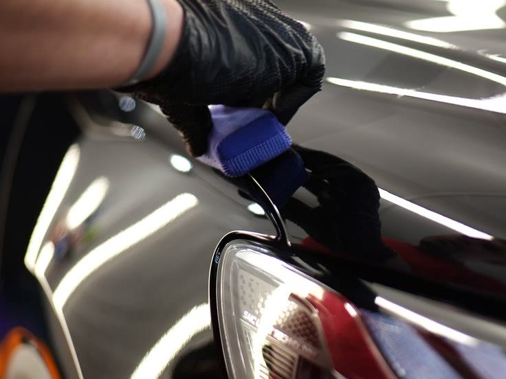 A coating applicator drawn across a gloss black fender