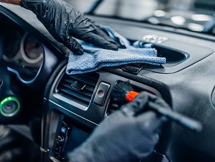 A dashboard and air vents being detailed by hand